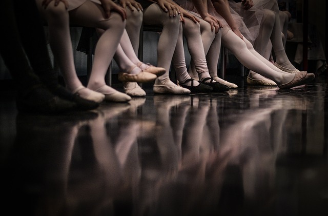 Baletky sedia na lavici vedľa seba s nohami na podlahe